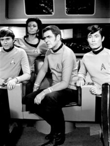 Luutnantti Uhura (2. vasemmalta)yhdessä muun upseeriston kanssa. Lähde: By NBC Television (eBay front back) [Public domain], via Wikimedia Commons